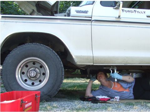 1979 Ford Bronco - A person works on the underside of a white 1979 Ford Bronco Custom truck.