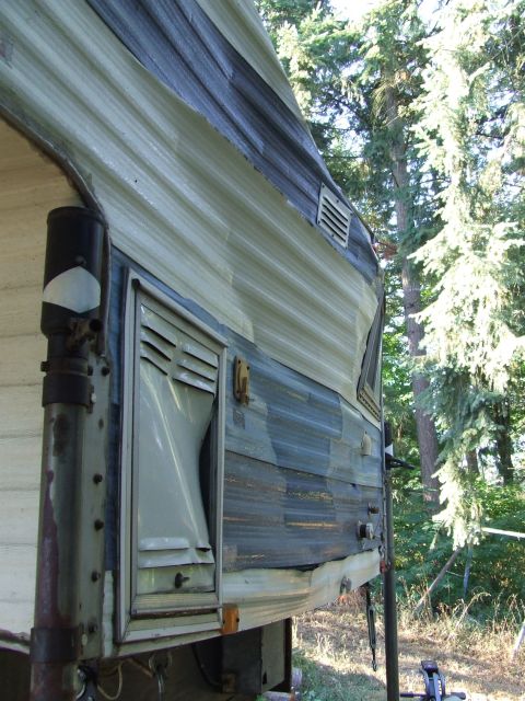 1996 Ford Bronco - The exterior of a camper shows weathered siding and a damaged vent cover.