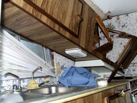 1996 Ford Bronco - The interior of a camper shows a kitchen area with wood cabinets, floral wallpaper, and a double sink.