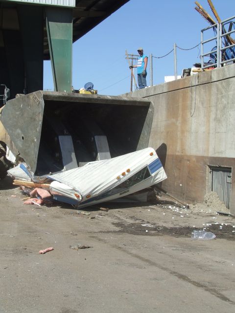 1996 Ford Bronco - A trailer is being crushed inside a large industrial dumpster.