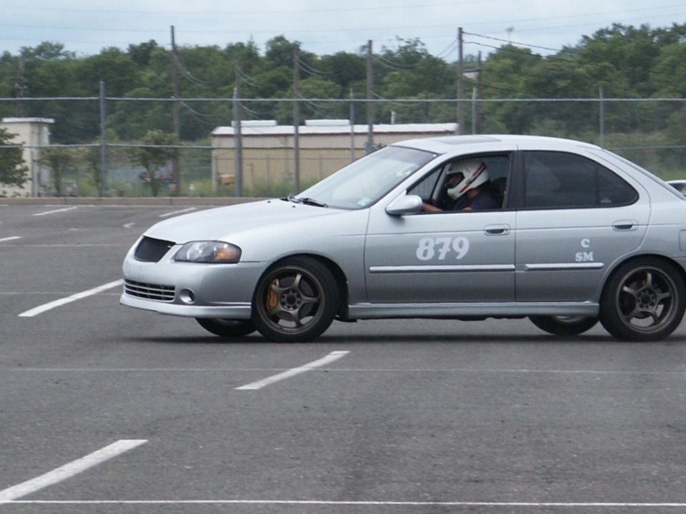 Silver sedan with racing number 879 on its side, driver wearing a helmet
