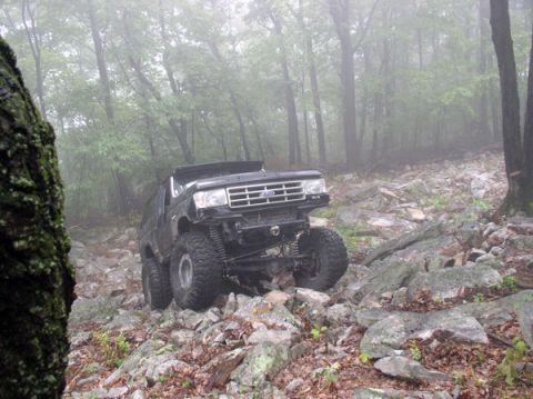 1988 Ford Bronco - This heavily modified Ford Bronco is tackling a challenging off-road course with large tires and lifted suspension.
