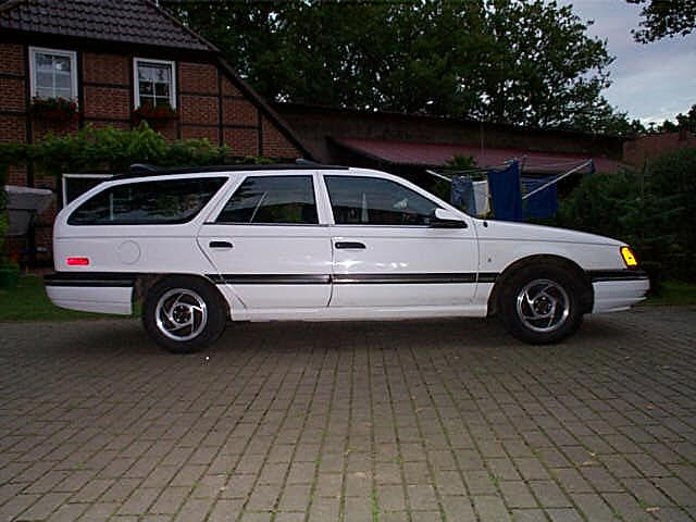 White Ford Taurus station wagon in profile parked on a brick courtyard