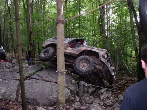 1988 Ford Bronco - An off-road vehicle navigates a rocky trail in a wooded area.
