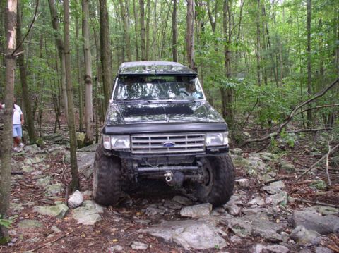 1988 Ford Bronco - This 1988 Ford Bronco navigates a challenging rocky path through a wooded area.
