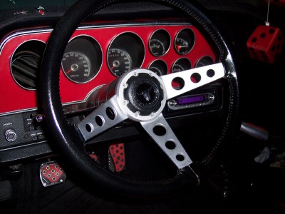 1972 Ford Ranchero - The interior of a car shows a custom steering wheel and a red dashboard with multiple gauges.