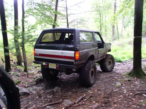 1988 Ford Bronco - This black 1988 Ford Bronco is equipped with large off-road tires and navigates a wooded trail.
