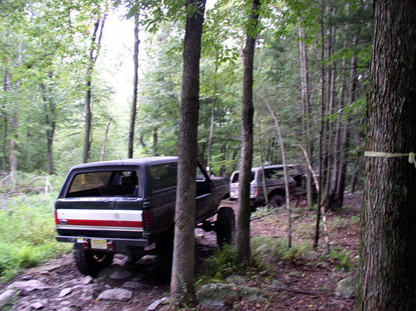 1988 Ford Bronco and another SUV on a rocky wooded trail