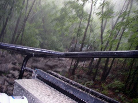 1988 Ford Bronco - Looking out from a vehicle during a rainy off-road excursion through a forest.