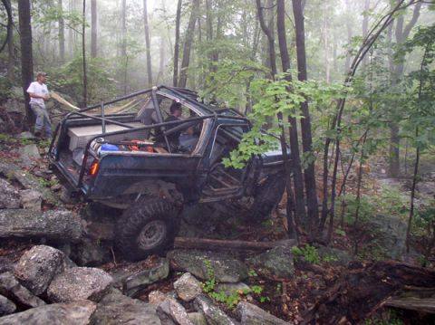 1988 Ford Bronco - Modified 1988 Ford Bronco navigating a rocky trail in a wooded area.