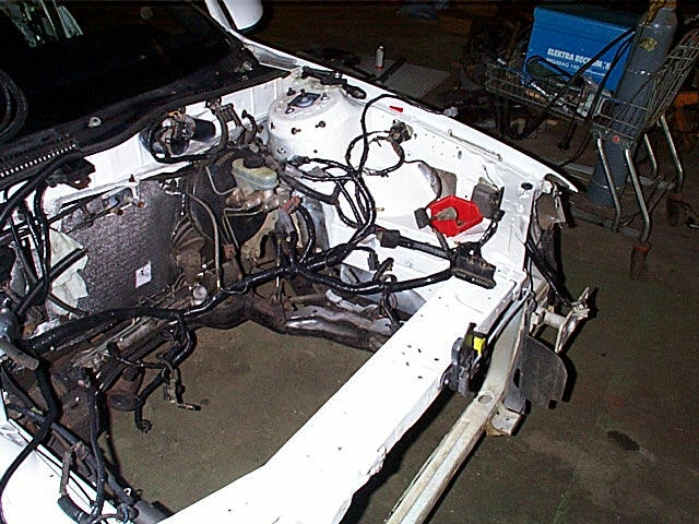 Empty engine bay painted white with brake master cylinder and wiring harness