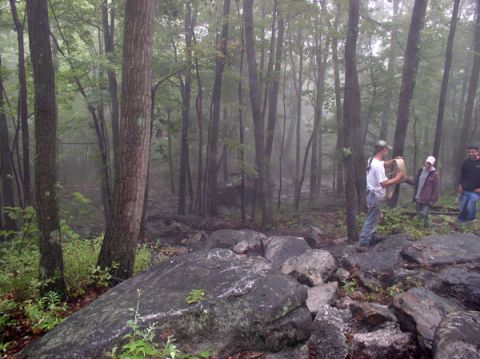1988 Ford Bronco - Three people stand in a rocky, wooded area with fog in the background.