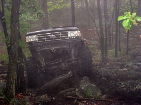 1988 Ford Bronco - Ford Bronco tackling rough terrain in a wooded area.