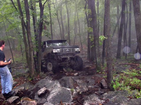 1988 Ford Bronco - A modified Ford Bronco tackles an off-road course in a misty forest.