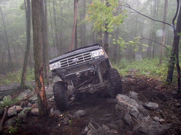 Ford Bronco climbing over rocks in a forest