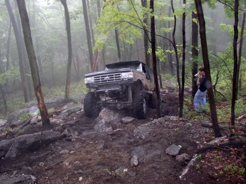 1988 Ford Bronco - A lifted 1987 Ford Bronco tackles a challenging off-road course in a misty woodland setting.