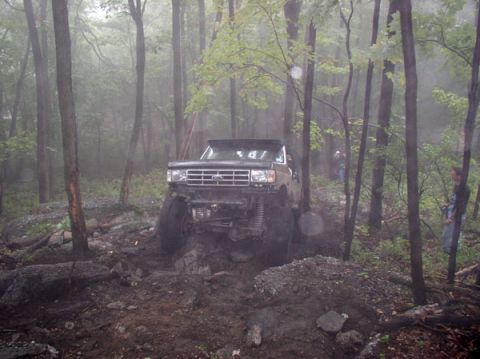 1988 Ford Bronco - Ford Bronco navigating a challenging off-road course in a wooded area.