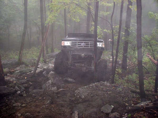 Ford Bronco going over rocks in a forest