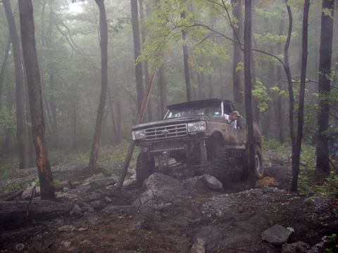 1988 Ford Bronco - A lifted Ford Bronco navigates a challenging, wooded off-road course.