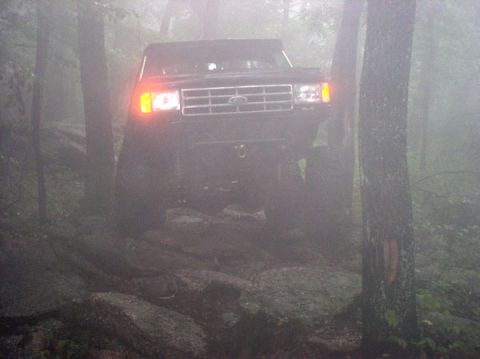 1988 Ford Bronco - Ford Bronco navigates a rocky trail through a foggy forest.