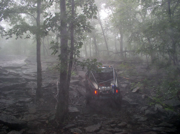 1988 Ford Bronco on a muddy, rocky trail in the woods