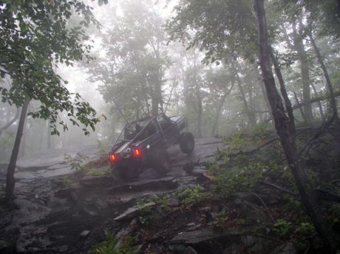 1988 Ford Bronco - A custom off-road buggy navigates a challenging, rocky incline amidst a foggy forest.