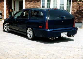 1990 Mercury Sable - Rear view of a dark blue station wagon, custom wheels and a quad exhaust system.