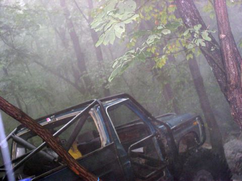 1988 Ford Bronco - A dark green 1988 Ford Bronco, equipped with a roll cage, is seen in a foggy forest setting.