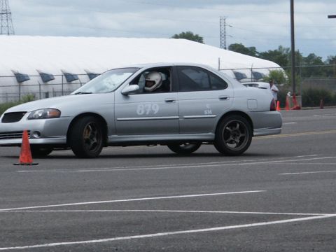 2001 Mercury Grand Marquis - Silver sedan with racing number 879 on the door is on a track with orange cones.