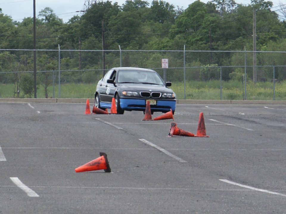 Front view of a dark BMW 3 Series sedan with blue lower body panels on a cone course
