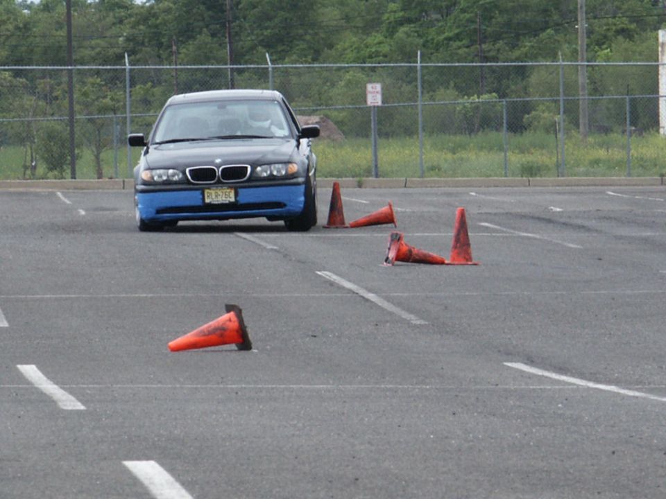 BMW 3 Series with blue front bumper and license plate RLR-76C, parked in a lot with orange cones