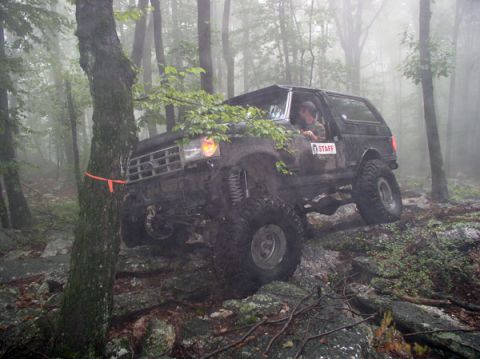 1988 Ford Bronco - A black 1988 Ford Bronco navigates a challenging, rocky trail through a misty forest.