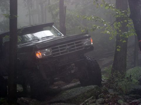1988 Ford Bronco - Ford Bronco tackles rough terrain in foggy forest conditions.