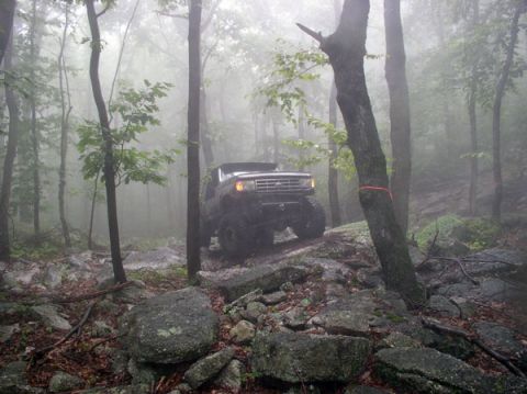 1988 Ford Bronco - A lifted Ford Bronco navigates a challenging, fog-shrouded off-road course.