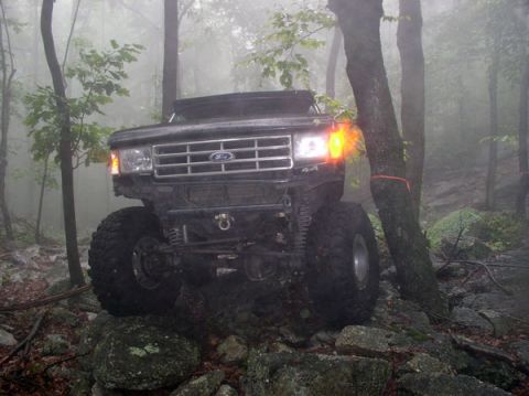 1988 Ford Bronco - A black 1988 Ford Bronco navigates a rocky, foggy forest trail.