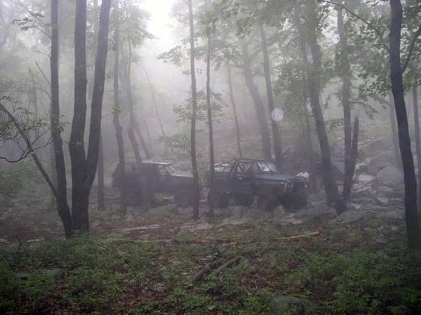 1988 Ford Bronco and another SUV off-roading in a foggy forest