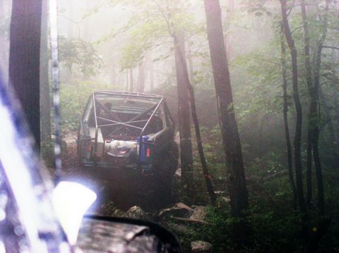 1988 Ford Bronco - An off-road vehicle navigates a foggy forest path, its roll cage clearly visible.