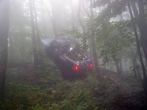 1988 Ford Bronco - Off-road vehicle stuck on a hill in foggy woods.