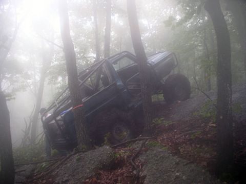 1988 Ford Bronco - A modified off-road vehicle navigates a challenging, fog-shrouded forest path.