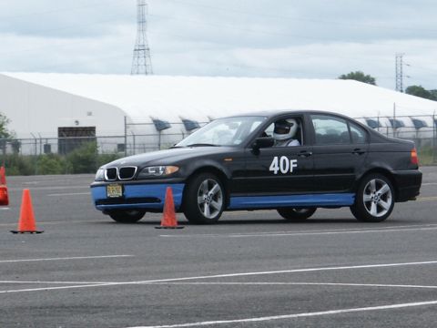 2001 Mercury Grand Marquis - A BMW sedan with racing numbers and safety gear is on a track, navigating around cones.