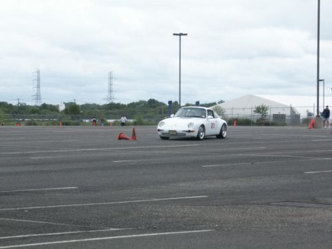2001 Mercury Grand Marquis - A white Porsche 911 navigates a course marked by orange cones on a cloudy day.