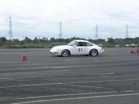 2001 Mercury Grand Marquis - A white Porsche 911 with racing number 21 navigates a course marked by orange cones on a cloudy day.