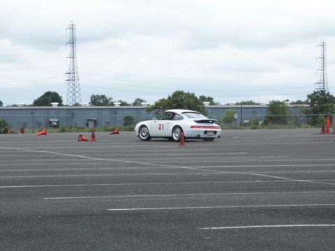 2001 Mercury Grand Marquis - A white Porsche 911 with racing number 21 navigates a course marked by orange cones on a cloudy day.