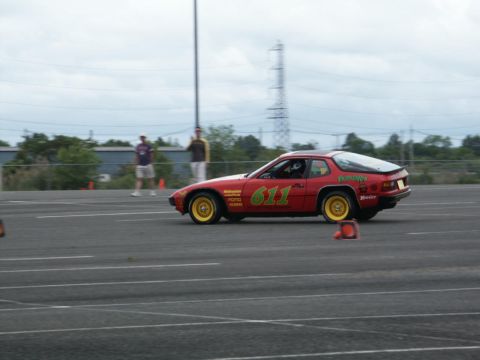 2001 Mercury Grand Marquis - A red coupe with racing decals and yellow wheels navigates a course marked by cones.