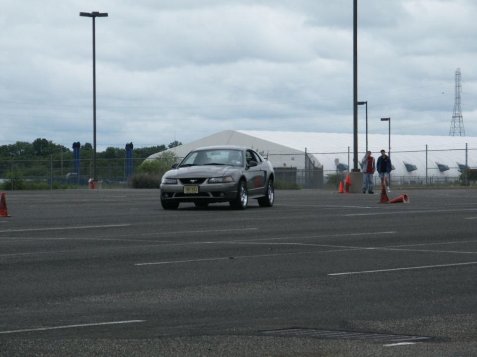 Gray Ford Mustang coupe driving on asphalt with orange cones