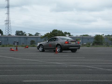 2001 Mercury Grand Marquis - Gray Ford Mustang with red number 10 on door, driving on asphalt course with orange cones.