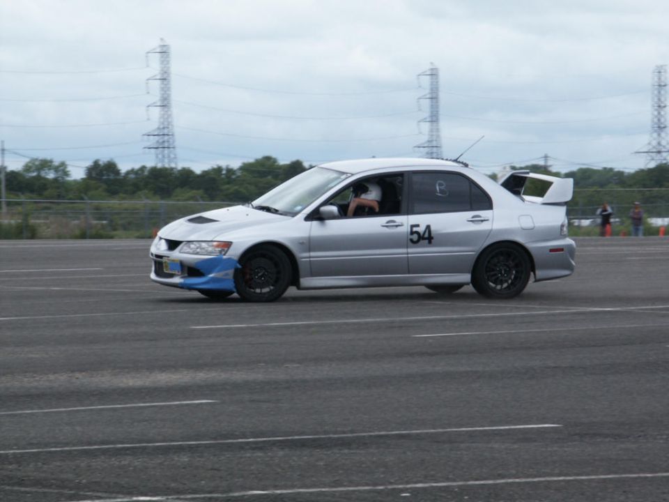 Silver Mitsubishi Lancer Evolution VIII with racing number 54 on the door and a large rear spoiler, on a track