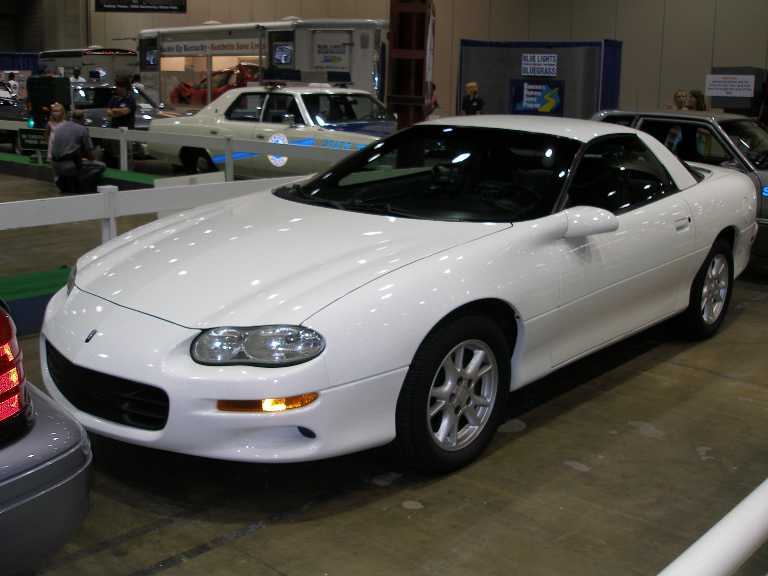 White Chevrolet Camaro coupe, front 3/4 view, at indoor auto show