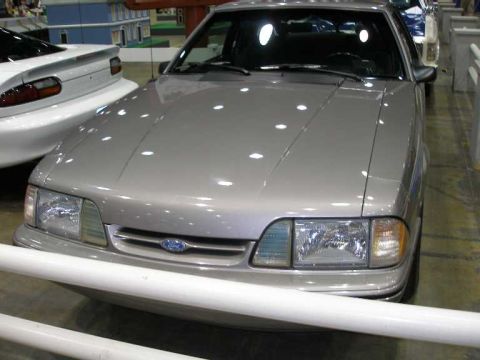 1998 Ford Crown Victoria - Front view of a silver-gray Ford Mustang (Fox body) coupe with a Ford badge in the grille, composite headlights and amber corner lights, di…