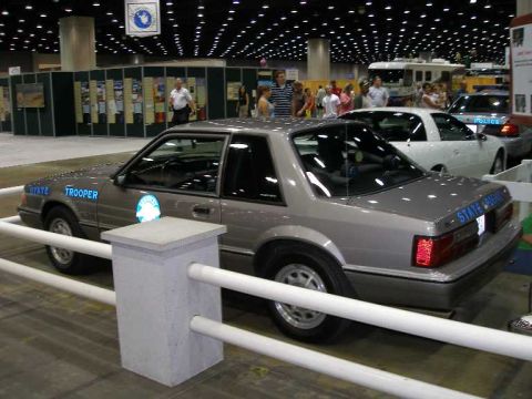 1998 Ford Crown Victoria - A gray/silver Ford Mustang two-door coupe displayed as a State Trooper police car, shown from the rear-side 3/4 angle with blue 'STATE TROO…